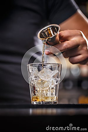 Barman is pouring alcohol from a jigger Stock Photo