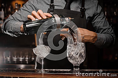 Barman pouring alcoholic drink into a glass using a jigger to prepare a cocktail Stock Photo