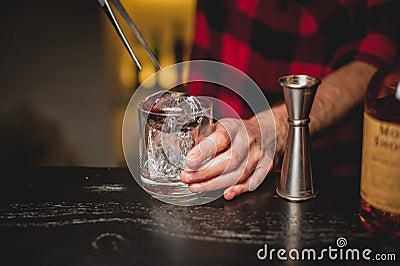 Barman pouring ice in glass.Bartender preparing cocktail drink. Stock Photo