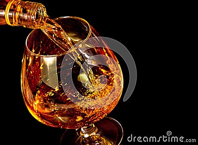 Barman pouring snifter of brandy in elegant typical cognac glass on black background Stock Photo