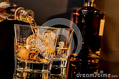 Barman pouring whiskey in front of whiskey glass and bottles Stock Photo