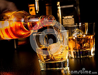 Barman pouring whiskey in front of whiskey glass and bottles Stock Photo