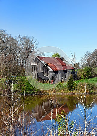 Barn and Sky Reflect in Still Water of Farm Pond Stock Photo