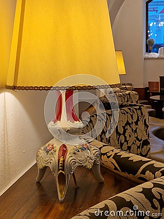 Baroque lamp on a night table next to a sofa spreading dimmed yellow light in the room Stock Photo