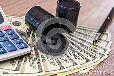 Barrels of oil with dollar money on wooden desk. Stock Photo