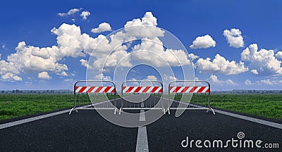 Metal barriers blocking a straight line against a blue sky with white clouds Stock Photo