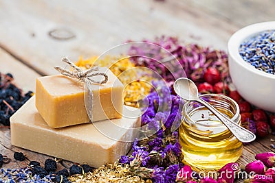 Bars of homemade soaps, honey or oil and heaps of healing herbs Stock Photo