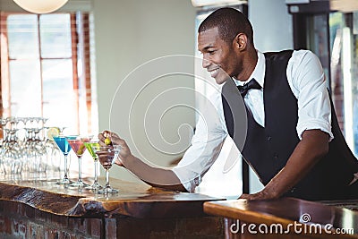 Bartender garnishing cocktail with olive Stock Photo