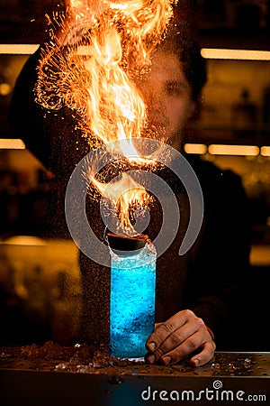 bartender sprinkling fired up blue alcohol drink with feijoa and ice Stock Photo