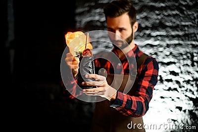 Bartender holds ceramic cup with cocktail and sets it on fire. Stock Photo