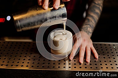 Bartender pouring fresh thick creamy alcoholic drink into a glass Stock Photo