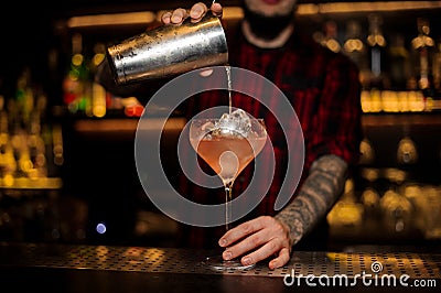 Bartender pourring a Sicilian Tonic cocktail from the steel shaker Stock Photo