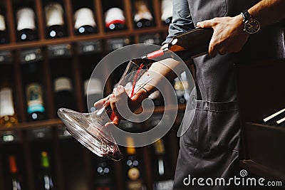 Bartender pours red wine in transparent vessel in cellar Stock Photo