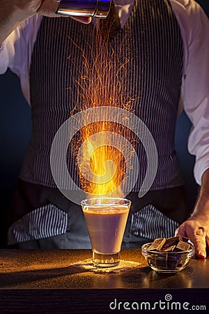 Bartender sprinkling cinnamon to burning Baileys comet cocktail Stock Photo