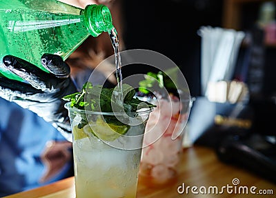 Bartender wearing medical latex black gloves,making mojito cocktail.Process of bartending in bar Stock Photo