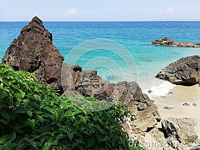 Basaltic volcanic rock on sandy beach Stock Photo