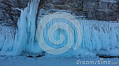 The base of the granite rock is covered with amazing icicles like lace frills. Stock Photo