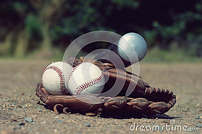 Baseball ball in leather glove with a baseball bat lying on the playground Stock Photo