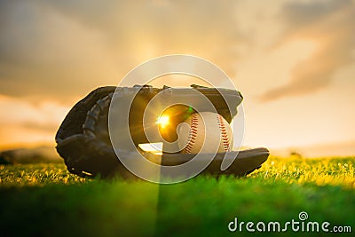 Baseball in glove in the lawn at sunset in the evening day with sun ray Stock Photo