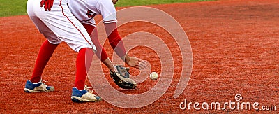 Baseball infielder fielding the ball on a red turf field Stock Photo