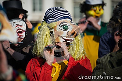 portrait of masked people wearing traditional costume playing flute parading in the street Editorial Stock Photo