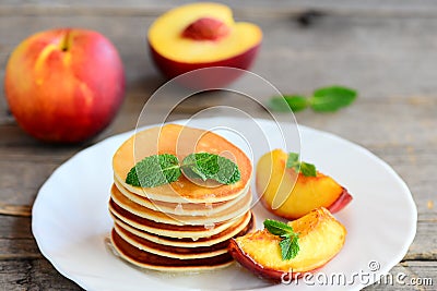 Basic pancakes with syrup and grilled nectarines on a serving plate and an old wooden table. Pancake recipe without butter Stock Photo