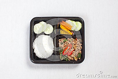 Basil fried rice with minced pork, put in a black plastic box, put on a white tablecloth, food box Stock Photo