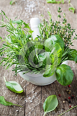 Basil, thyme, rosemary and tarragon. Mortar bowl with fresh aromatic herbs for cooking. Stock Photo