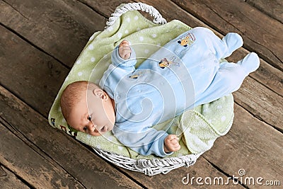 Basket with baby, wooden background. Stock Photo