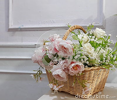 A basket of decorative flowers on a white table Stock Photo