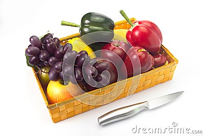 Basket of fake fruit with a knife on a white background. Stock Photo