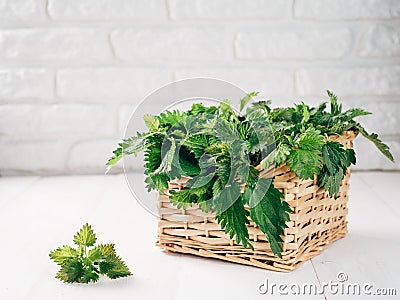 Basket of fresh stinging nettle leaves on wooden table Stock Photo