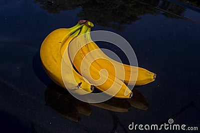 basket of yellow ripe bananas on a black reflective Stock Photo