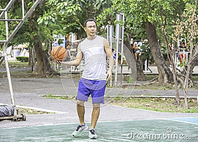 Basketball in hand Asian man to exercise Background tree at Bang Yai Park , Nonthaburi in Thailand Stock Photo