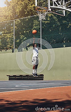 Basketball, jump and athlete scoring a goal during a match or training on an outdoor court. Fitness, sports and man Stock Photo