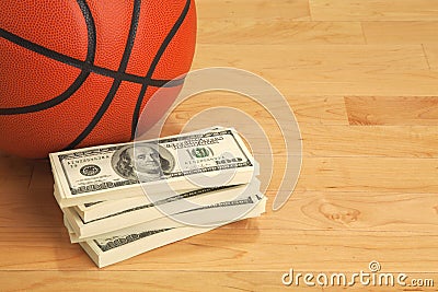 Basketball and one hundred dollar bills on wooden court floor Stock Photo