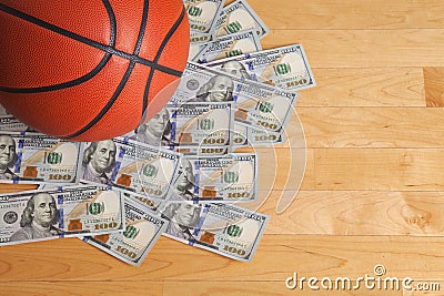 Basketball on pile of one hundred dollar bills Stock Photo