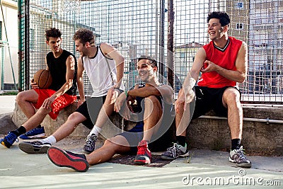 Basketball players take a break sitting on a low wall Stock Photo