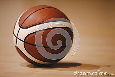 Basketball on Wooden Court Floor Close Up with Blurred Arena in Background Stock Photo