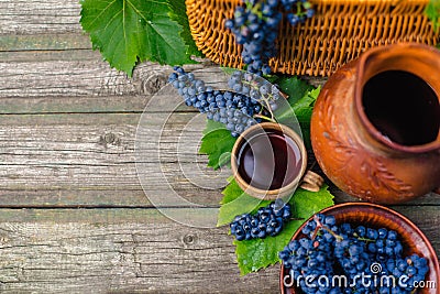 Baskets and bowl with grapes beside Jar and cup with wine stand on on rustic wood. Wine making background. Stock Photo