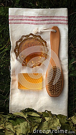 Bath soap lies on a light towel. A birch broom, a body brush and natural honey lie nearby. Set of accessories for sauna and steam Stock Photo