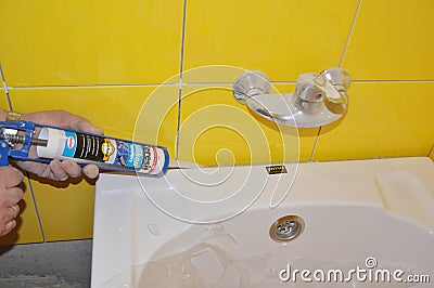 Bath tube installation with Silicone Bathroom Caulk, water tap in the yellow tiled bathroom. Repair bathroom with new bath tube. Editorial Stock Photo