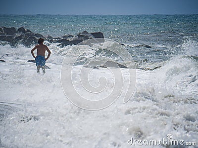 Bather on the beach during a heavy storm. Waves crashing powerfully to shore Editorial Stock Photo