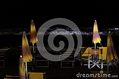 Bathing establishments with deck chairs and umbrellas on the beach at night Stock Photo