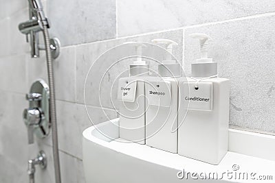 Bathroom hotel amenity, shower gel, shampoo, and conditioner in luxury ceramics container with labels on wooden shelf Stock Photo