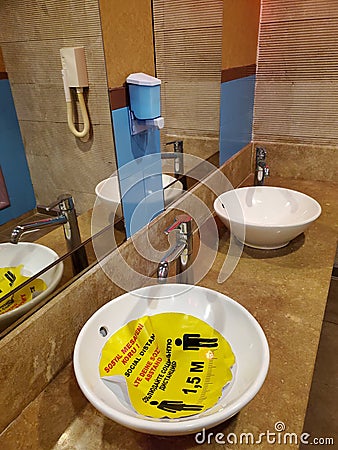 Bathroom interior with yellow sticker in sink about keeping social distance Editorial Stock Photo