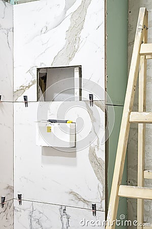 Bathroom renovation concept. Marble ceramic tiles with spacers and grey cement walls in bathroom, renovating and working in toilet Stock Photo