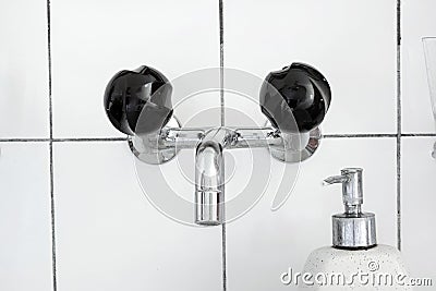 Bathroom sink and faucet with black mixing knobs and liquid soap dispenser. Close up shot, no people Stock Photo
