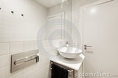 Bathroom with white wood cabinets, white porcelain hemispherical sink, large built-in mirror, tile work, and white wood door Stock Photo