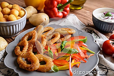 Batter fried squid rings with potato croquettes and pepper salad Stock Photo